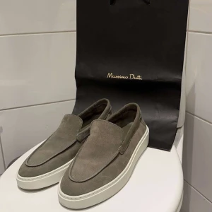 Massimo dutti - Snygga grå loafers i mocka från Massimo Dutti. De har en stilren design med vit sula och är perfekta för en avslappnad men ändå elegant look. Passar bra till både jeans och chinos. Storlek 43 men passar 44