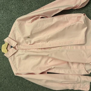 Ljusrosa skjorta från Ralph Lauren - Snygg ljusrosa skjorta från Ralph Lauren med klassisk krage och knäppning framtill. Skjortan har lång ärm och ikoniska broderade loggan på bröstet. 