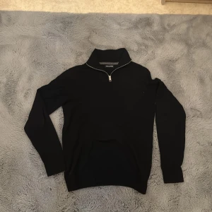 Svart half zip tröja Jack & Jones XS - Svart långärmad tröja från Jack & Jones i storlek XS. Tröjan har en hög krage med half zip-dragkedja och är tillverkad i mjukt stickat material. Perfekt för lager-på-lager och enkel att matcha med jeans eller chinos.