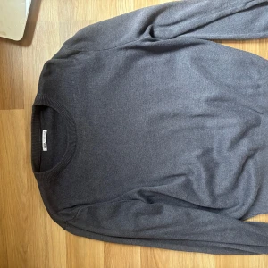 Mörkblå stickad tröja från Zara - En stilren mörkblå stickad tröja från Zara med rund halsringning och långa ärmar. Tröjan har en klassisk passform och är perfekt för lager-på-lager. Materialet känns mjukt och passar till många olika outfits.