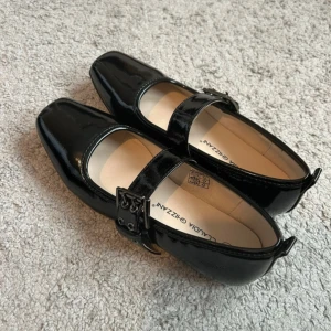 Svarta ballerinaskor  - Stilrena svarta ballerinaskor i lack från Claudia Ghizzani. Skorna har fyrkantig tå, bred rem med spänne och platt sula. Använda 1-2ggr men har inga tecken på användning 🩷storlek 37 men passar mer som 36