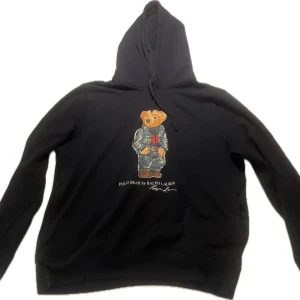 Mörkblå hoodie Polo Bear Ralph Lauren - Mörkblå hoodie från Ralph Lauren med ikoniska Polo Bear-trycket framtill. Tröjan har huva med snörning och lång ärm. Köpt i rl butik för 2700, 9/10 skick. Kan gå ner i pris vid snabb affär