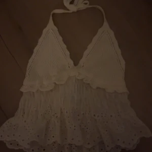 Vit spetsig linnetopp från Zara XS - Supersöt vit linnetopp från Zara med knyt i nacken och broderade spetsdetaljer. Toppen har volangkant och hålmönster nertill, samt stickad överdel. Perfekt för sommarens alla tillfällen! Aldrig använd, med prislapp kvar💗