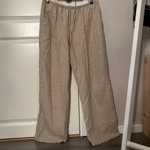 Beiga linnebyxor från Gina Tricot - Snygga beiga linnebyxor från Gina Tricot med avslappnad passform och resår i midjan. Byxorna har raka, vida ben och är perfekta för en chill och stilren look. Lätta och luftiga, passar grymt till varma dagar. Använda endast 1 gång, pris kan diskuteras 🌸