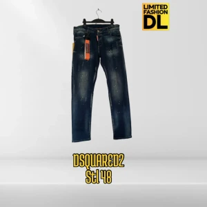 Mörkblå jeans från Dsquared2 stl 48 - Snygga mörkblå jeans från Dsquared2 i storlek 48. Jeansen har en tvättad look med ljusa partier och små färgstänk för en cool, unik stil. Klassisk femficksmodell med orange detaljer och tillverkade i Italien. Perfekta för dig som vill sticka ut.