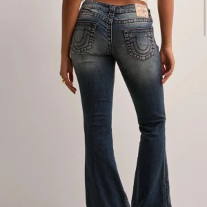 True Religion bootcut jeans blå - Snygga blå jeans från True Religion med bootcut passform och låg midja. Jeansen är sparsamt använda och i super bra skick. De är uppsydda någon cm och passar mig som är ca 160 bra. Stl 26. Om ni önskar bild av hur de är uppsydda så är det bara att höra av sig. 🩷