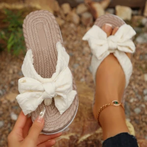 Beige sandaler med stor rosett - Snygga sandaler i beige med en stor vit rosett framtill. Sulan har flätad look och ovandelen är mjuk och textil. Perfekta för varma dagar när du vill ha en söt och avslappnad stil.
