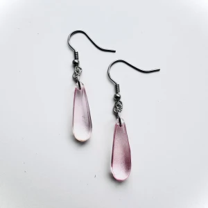 Nickelfria örhängen, rosa droppe - Snygga örhängen med droppformade glashängen i transparent rosa. Krokarna är i silverfärgad nickelfri kirurgisk stål och ger en stilren look. Perfekta för att addera lite färg till din outfit. 