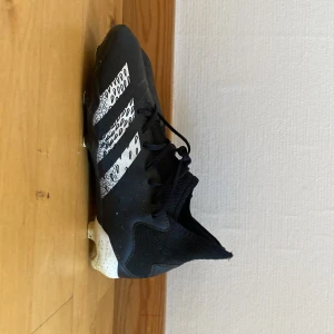 Adidas Predator svarta fotbollsskor - Snygga svarta Adidas Predator. Skorna har snören och en strumpliknande passform för extra komfort. Perfekta för dig som vill dominera på planen med stil.