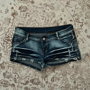lowrise jeanshorts - Snygga mörkblå jeansshorts från Pai med slitna detaljer och fransig nederkant. Perfekt nu inför sommaren! köpte de i visby men är fortfarande i perfekt skick! längd: 22cm midja: 40cm