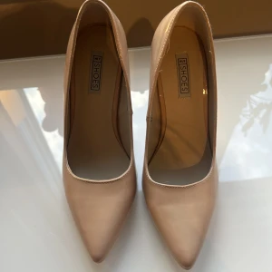 Beiga pumps med spetsig tå från Nelly - Snygga beiga pumps från Nelly med spetsig tå och hög klack. Skorna har en glansig finish som ger en elegant look. Använda en gång inomhus, så det är väldigt bra skick! Pris kan diskuteras💕