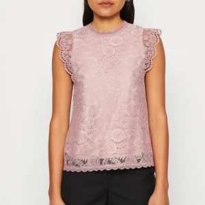 Ljuslila spetsblus från Pieces - Superfin ljuslila blus från Pieces med detaljerad spets och blommigt mönster. Ärmlös modell med volangkant vid axlarna och rund halsringning. Perfekt för dig som gillar romantisk och feminin stil.