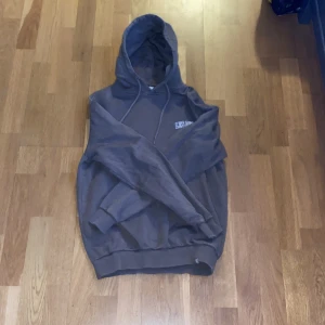 Brun hoodie från Les Deux - Säljer en brun hoodie från Les Deux med broderad logga på bröstet. Tröjan har huva med snörning och ribbade muddar vid ärmslut och nederkant. Perfekt för en chill och avslappnad stil.