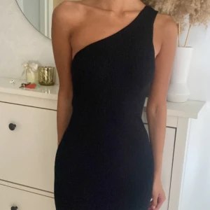 Svart oneshoulder ribbad klänning - Assymetrisk klänning från MANGO, bara använd en gång och är i väldigt bra skick i mjukt material! 🩷finns en slits längre ner vid benen på vänster sida!