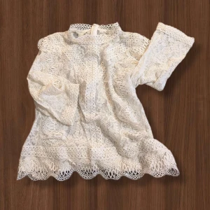 Vit blus/topp från Monsoon - Exklusiv, elegant, superfin vit blus/topp från Monsoon med 3/4-ärm och hög hals. Blusen har vackra broderade detaljer, vågig kant nertill och dragkedja i nacken. Det är ingen tunn blus, utan ganska så kraftig. Jättefin kvalité.