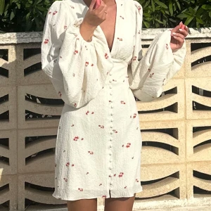 Vit blommig kortklänning med knappar - Säljer min Adoore klänning som tyvärr är lite liten för mig. Jag har kvar lappen då den endast är använd en gång när jag tog bilder i den🤍 Hur fin som helst🥹 STRL 32.