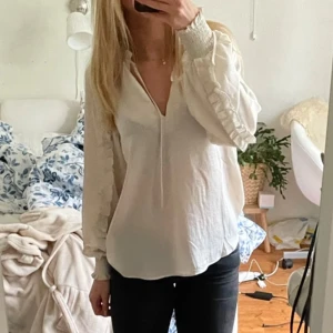 Vit blus med v-ringning - Säljer en stilren vit blus med v-ringning och långa ärmar. Blusen har en lös passform och är tillverkad i ett lätt bomullsliknande material. Perfekt att styla med jeans eller kjol för en fräsch look.