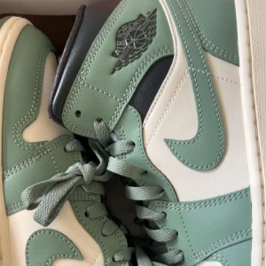 Nike Air Jordan 1 i mintgrön och vit - 🇸🇪Säljer ett par Nike Air Jordan 1 med mintgröna och vita paneler. Skorna har klassisk hög siluett, snörning och ikoniska Air Jordan-loggan på sidan. Perfekta för dig som vill sticka ut med stilrena sneakers.🇫🇮Vaalean vihreet Nike Air Jordanit, käyttämättömät. Ovh. 169€