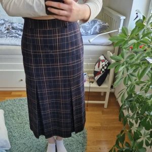 Mörkblå rutig långkjol från Stockh LM - Säljer en mörkblå långkjol från Stockh LM med rutigt mönster i beige och brunt. Rak, stilren form med fickor och underkjol