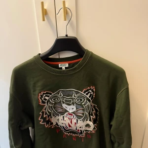 Olivgrön sweatshirt från Kenzo - Säljer en olivgrön sweatshirt från Kenzo med tigerbrodyr och logga framtill.