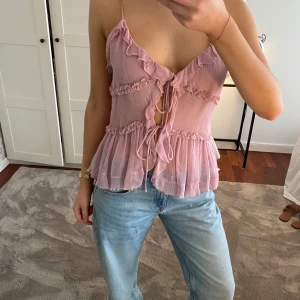 Volangtopp Zara  - Tunn, rosa volangtopp från Zara med knyt framtill. Endast använd 2 gånger! Axelbanden har jag sytt kortare eftersom de var för långa, se bild 3 och bild 5 för hur det ser ut där jag sytt fast banden på nytt där bak (ps det syns knappt). Toppen är från Zara och är i storlek S men jag har klippt av lappen där bak eftersom den syntes igenom och kliade… skriv för mått på axelbanden efter jag sytt om dem om du är intresserad! Pris kan också diskuteras🩷🩷