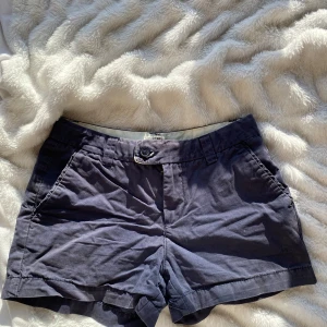 Mörkblå shorts från Hampton Republic - Snygga mörkblå shorts från Hampton Republic med klassisk design. De har fickor fram och bak, knapp och dragkedja i midjan samt bälteshällor. Perfekta för varma dagar och enkel att matcha med olika toppar💕