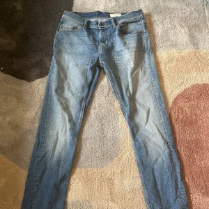 Blå jeans från Tiger of Sweden - Säljer ett par klassiska blå jeans från Tiger of Sweden. Byxorna har fem fickor, normal passform och raka ben. Perfekta för en stilren och enkel look. Jeansmaterialet är mjukt och bekvämt.