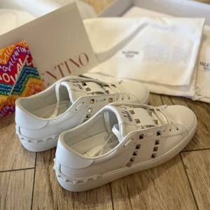 Vita Valentino Garavani Rockstud sneakers - Säljer ett par vita Valentino Garavani Rockstud sneakers med ikoniska nitar längs sidorna och bak. Har endast använt dessa en gång för att dom är för små för mig! 🤍 Ordinarie pris är 8500kr