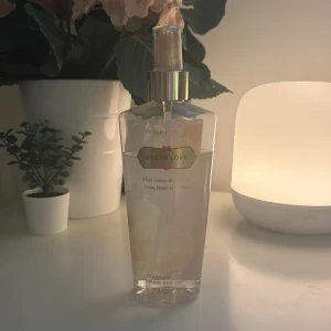 Sheer Love Body Mist från Victoria's Secret - Fräsch body mist från Victoria's Secret i doften Sheer Love. Flaskan är transparent med guldigt spraymunstycke och har en ljusrosa etikett. Doften är en blandning av vit bomull och ros, perfekt för dig som gillar lätta och blommiga parfymer.