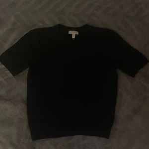 Svart stickad kortärmad tröja från H&M - Säljer en svart stickad tröja från H&M med korta ärmar och rund halsringning. Mjuk och bekväm, passar till många tillfällen.