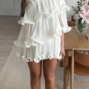 Lojsan Wallin x NA-KD - Superfin vit kortklänning med flera lager volanger och plisserat tyg. Endast använd två gånger, säljer pga den är för stor för mig. Pris kan diskuteras då jag vill rensa ut mycket 