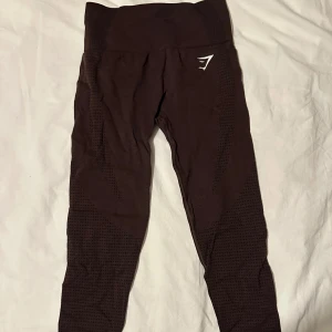 Bruna seamless tights från Gymshark - Mörkbruna tights från Gymshark med hög midja och seamless design. Perfekta för träning och ger en tight passform samt bekväma. Säljer på grund att jag inte använder. Har använts max 3 gånger. Köpt på Gymshark hemsida och är slutsålda. Om ni är intresserade av att köpa hela set. (Tränings tröja + leggings) kan ni få ett lägre paket pris. Kontakta mig vid intresse av paketpriset! 