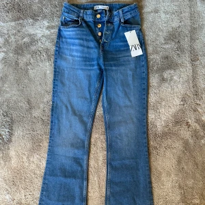Bootcut jeans från Zara med knappar - Snygga blå bootcut jeans från Zara med hög midja och  guldknappar framtill. Stretchigt denimtyg. Endast provat de hemma, prislappen är fortfarande kvar. 