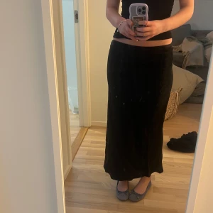 Svart långkjol i satin från Dagmar  - Säljer en svart långkjol i satin som går att ha både lågmidjat och högmidjat. Kjolen har en stilren och enkel design utan synliga detaljer, perfekt för dig som gillar en klassisk look. Snygg att matcha med både toppar och stickade tröjor. Aldrig kommit till användning tyvärr och är från House Of Dagmar. Nypris 3800 kr