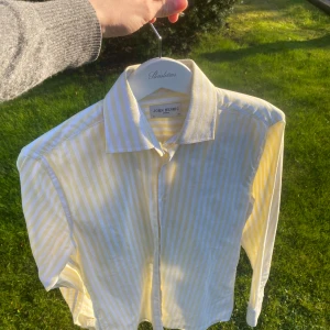 Gul- och vitrandig skjorta från John Henric - Snygg skjorta från John Henric med gula och vita ränder. Klassisk krage och knäppning framtill. Perfekt för dig som vill ha en fräsch och somrig look. Skjortan är i ett lätt och svalt material.