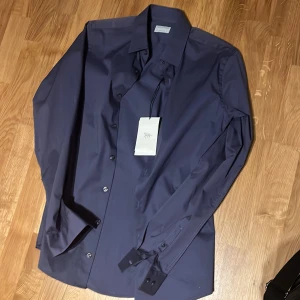 Tiger of Sweden skjorta - Säljer en mörkblå skjorta från Tiger of Sweden i extra slim fit. Skjortan har klassisk krage, långa ärmar och knäppning framtill. Perfekt för dig som gillar en stilren och tajt passform. Märkeslapp sitter kvar. Sitter som S