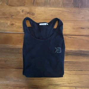 Svart linnetopp från Better Bodies - Svart träningslinne från Better Bodies med brottarrygg och diskret logga på bröstet. Perfekt för gymmet eller andra träningspass. Tunt och mjukt material som ger bra rörelsefrihet.