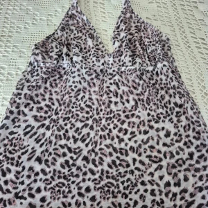 Sunkini Tankini stl L - Säljer en snygg strandtankini med leopardmönster. Tankinin är i halterneckmodell ned knyt i nacken. Förstärkt över bysten med extra tyg. Materialet släpper igenom solen precis som sunkinis övriga plagg. Perfekt till svarta bikinibyxor! Aldrig använd då den inte passade mig. Stl L. Nypris: 495:-