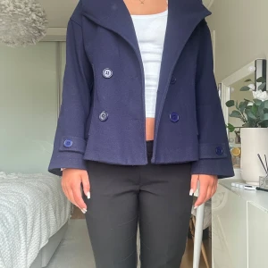 Mörkblå kappa med knappar - Säljer en mörkblå kappa från Design by Si, i storleken XS/S. Modellen har en bred krage och dubbelknäppning. Perfekt för dig som vill ha en stilren look. Pris kan diskuteras☺️💕