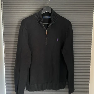 Stickad Ralph Lauren Halfzip - Säljer en svart stickad halvzip tröja från Polo Ralph Lauren. Tröjan är i använt skick: urtvättad. Tröjan har däremot inga tydliga skador. Tröjan är stl L men på grund av urtvättning är den kortare i midjan. Passar bättre till de som bär M.