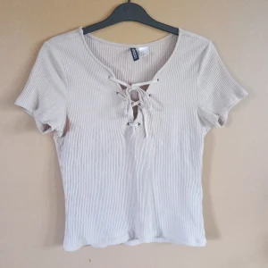Ljusrosa topp - Ljusrosa ribbad topp från H&M med korta ärmar och snygg snörningsdetalj framtill. Sparsamt använd och fint skick. Storlek S 💕