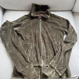 Olivgrön velourjacka från H&M L.O.G.G. - Säljer en olivgrön velourjacka från H&M L.O.G.G. i storlek XS. Jackan har dragkedja framtill, hög krage och två fickor. Perfekt för en avslappnad stil och mjuk känsla.
