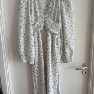 Gina trico5 Vit blommig långklänning fr - Superfin vit långklänning med små blå och gröna blommor från Gina tricot. Slutsåld från förra året. Storlek xs