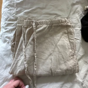 Beiga linnebyxor från Gina Tricot - Säljer ett par beiga linnebyxor från Gina Tricot. Byxorna har en avslappnad passform och är perfekta för varmare dagar. Materialet är svalt och luftigt linne. Stl S/M