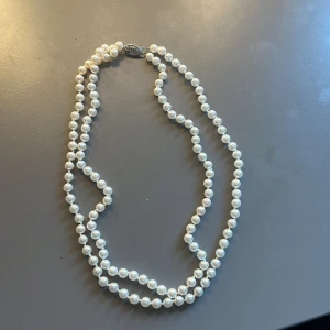 Pärlhalsband med silverfärvat spänne - Handgjort halsband med vita pärlor i två rader och ett dekorativt silverfärgat spänne. 