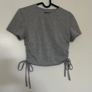 Grå t-shirt med detaljer på sidorna - Grå tröja med detaljer på sidorna, från shein strl XS, väldigt fin o väl använd och väl omhändertagen. 🤍