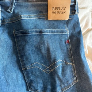 Blå Replay Hyperflex Anbass jeans  - Säljer ett par blå Replay Hyperflex Anbass jeans med klassisk femficksdesign och snygga sömmar på bakfickan. Jeansen har normal passform och är tillverkade i stretchigt material för extra komfort. Midjemått W31 och längd L32.