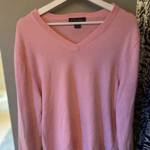 Ljusrosa v-ringad tröja från Brooks Brothers - Säljer en ljusrosa v-ringad tröja från Brooks Brothers i mjuk bomull. Tröjan har lång ärm och klassisk passform, perfekt för en stilren look. Enkel och tidlös design som passar till mycket.
