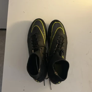Svarta Nike fotbollsskor med gula detaljer - Säljer ett par svarta Nike Mercurial fotbollsskor med gula detaljer i storlek 43.