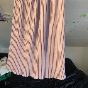 Lila långkjol med svarta ränder från H&M - Säljer en lila långkjol från H&M med svarta vertikala ränder. Kjolen har resår i midjan och ett luftigt, rakt fall. Perfekt för dig som gillar en stilren och enkel look med lite extra färg.